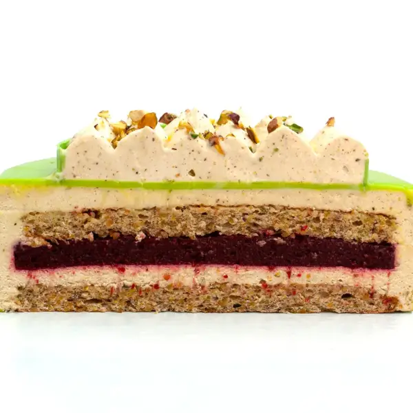 Pistáciovo-čerešňová torta – rozrezaná, viditeľné vrstvy jemného pistáciového krému a sviežej čerešňovej náplne v modernom mousse prevedení.