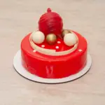 Vianočný tort v červenej zrkadlovej glazúre so šokoládovou dekoráciou v tvare vianočných gulí.
